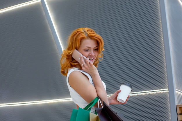 Jonge vrouwen praten aan de telefoon met pakketten winkelen in moderne mall. winkelen concept. black friday-concept. gelukkige vrouwen. pakketten houden.