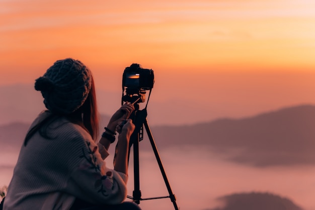 Jonge vrouwenfotograaf die beeld van landschap nemen wanneer zonsopgang bij bergpiek.