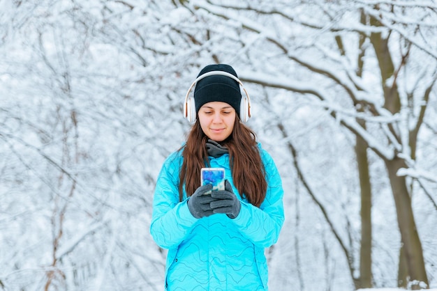 Jonge vrouwengang in besneeuwde dag met hoofdtelefoon