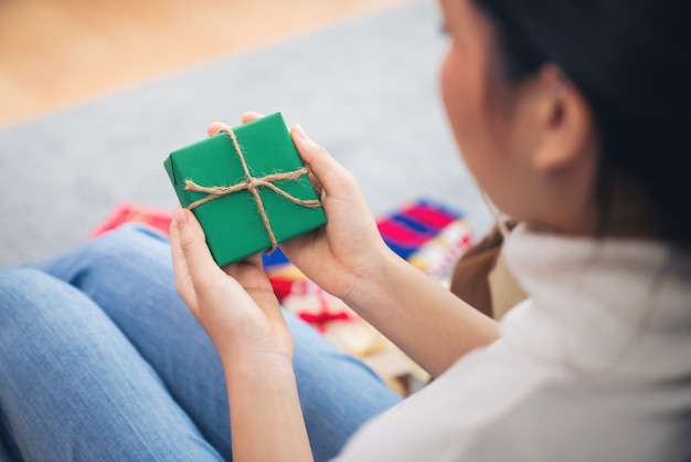 Jonge vrouwenhanden die groene giftdoos in het huis houden, Concept Kerstmis, Nieuwjaar en verjaardag.