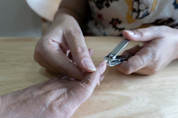 Jonge vrouwenhanden helpen bij het knippen van nagels met een nagelknipper voor oudere vrouwen