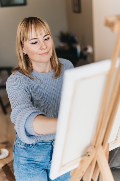 Jonge vrouwenkunstenaar die een beeld in studio schildert