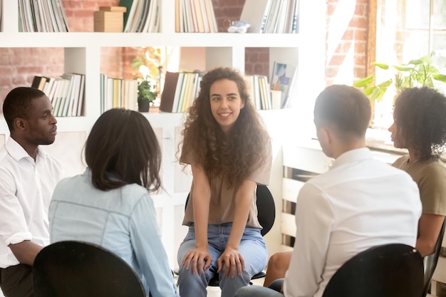 Foto jonge vrouwenpsycholoog die in een cirkel zit tussen diverse mensen die praten en delen tijdens therapievriendengroep hebben discussieondersteunende hulp bij teamvergaderingen die zakelijke bedrijfstraining adviseren