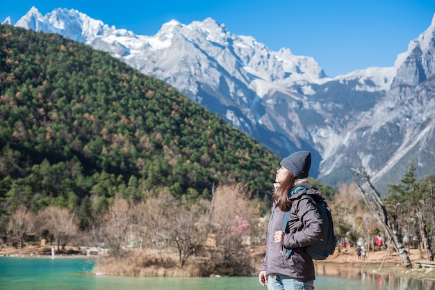 Jonge vrouwenreiziger die in Blue Moon Valley, oriëntatiepunt en populaire vlek binnen het Jade Dragon Snow Mountain Scenic Area, dichtbij de Oude Stad van Lijiang reizen. Lijiang, Yunnan, China. Solo reisconcept