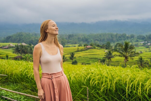 Jonge vrouwenreiziger op Mooie Jatiluwih-rijstterrassen tegen de achtergrond van beroemde vulkanen in Bali, Indonesië.