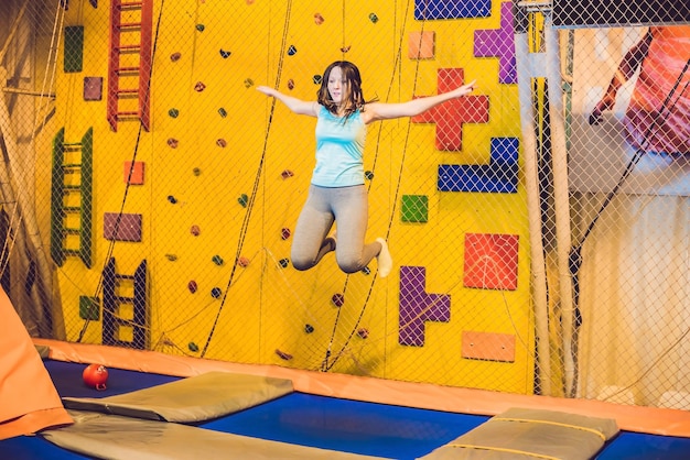 Jonge vrouwensportman die op een trampoline in geschiktheidspark springt en oefening binnenshuis doet