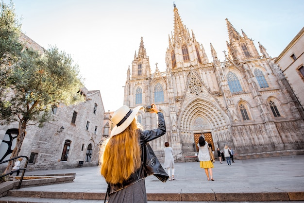 Jonge vrouwentoerist die met telefoon beroemde heilige Eulalia-kerk fotografeert tijdens het ochtendlicht in de stad van Barcelona