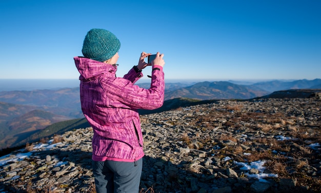 Jonge vrouwenwandelaar die beeld met haar smartphone neemt