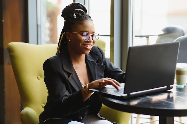 Jonge vrouwenzitting in een koffie die aan laptop werkt