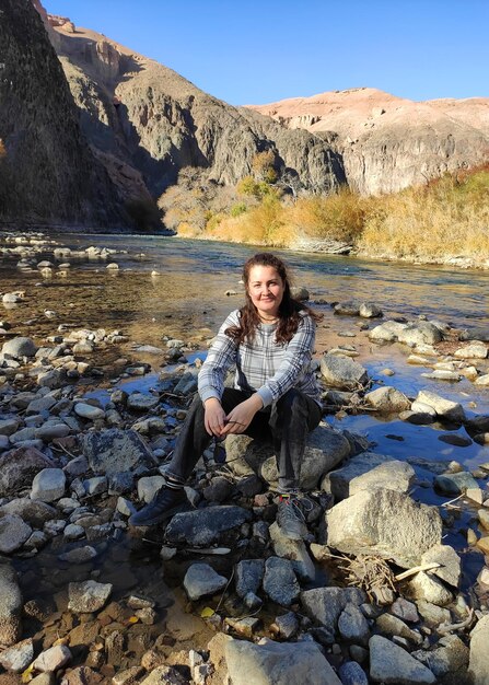 Jonge vrouwenzitting op de rots in rivier Charyn