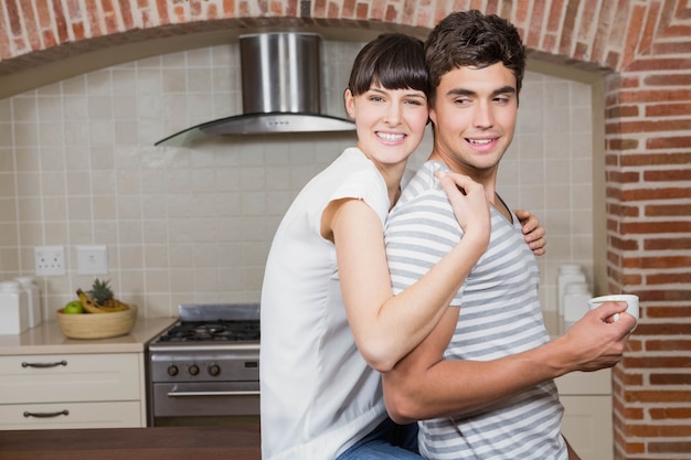 Jonge vrouwenzitting op keuken worktop en de omhelzende man