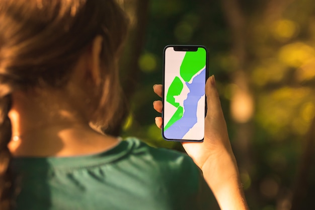 Jonge wandelaar gebruikt mobiele telefoon voor navigatie in het bos, bos achtergrondfoto