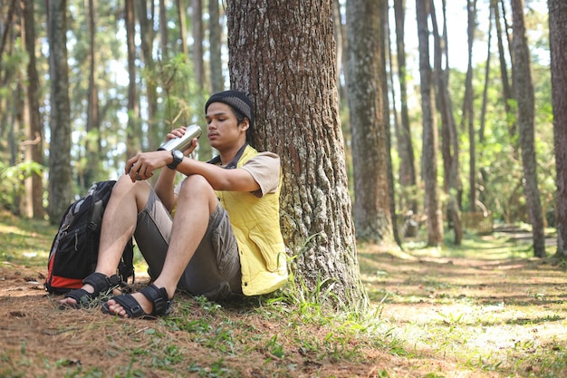 Jonge wandelaar man zittend rust drinken water uit fles na wandelen reizen natuur en avontuurlijke reis
