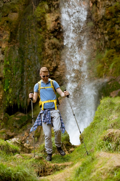 Jonge wandelaar stopte naast een bergwaterval om uit te rusten