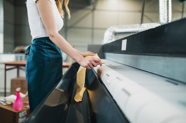 Jonge wasserijmedewerker klopt het linnen op de automatische machine bij de stomerij.