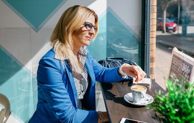 Jonge werkende vrouw die koffie roert in een café