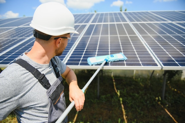 Jonge werknemer die zonnepanelen schoonmaakt