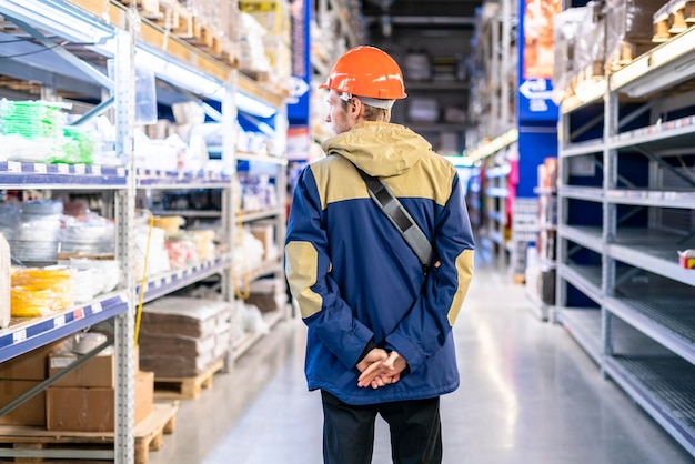 jonge werknemer in beschermende helm sorteert producten op de markt b