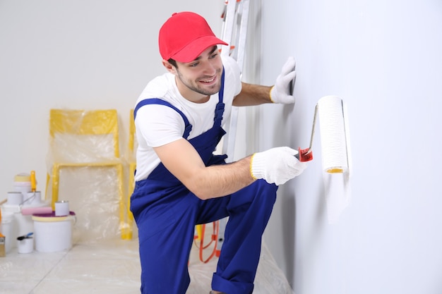 Jonge werknemer schilderij muur in kamer