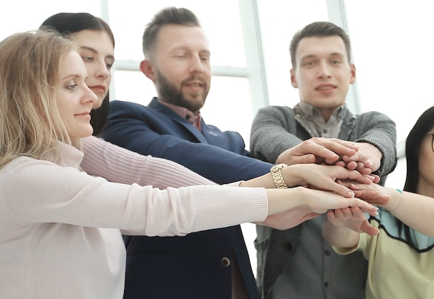 Jonge werknemers slaan hun handen over het bureau. het concept van teamwerk