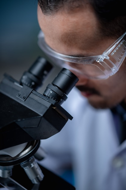 Foto jonge wetenschapper die door een microscoop in een laboratorium kijkt. jonge wetenschapper die wat onderzoek doet.