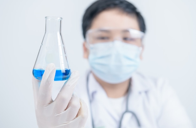 Jonge wetenschappers die blauw vloeibaar chemisch product in erlenmeyer houden. covid-19 testen in laboratorium en gezondheidszorg en medisch concept.