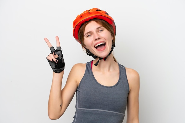 Jonge wielrenner engelse vrouw geïsoleerd op een witte achtergrond glimlachend en overwinningsteken tonen