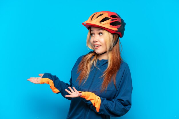 Jonge wielrenner meisje geïsoleerd op blauwe achtergrond met verrassing expressie terwijl op zoek naar kant
