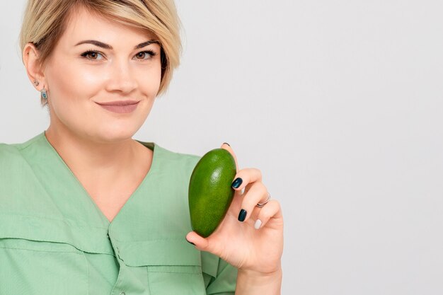 Jonge womanis die een avocado houdt.