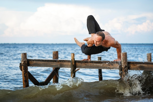 Foto jonge yogatrainer die yoga-oefeningen doet op een houten pier aan de kust van zee of rivier