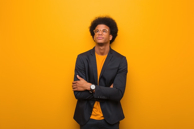 Jonge zakelijke Afro-Amerikaanse man over een oranje muur moe en verveeld