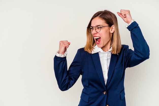 Jonge zakelijke blanke vrouw geïsoleerd op wit verhogen vuist na een overwinning, winnaar concept.