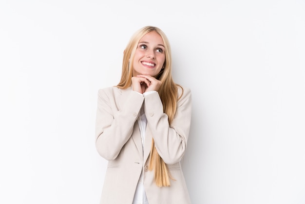 Jonge zakelijke blonde vrouw houdt handen onder de kin, kijkt gelukkig opzij