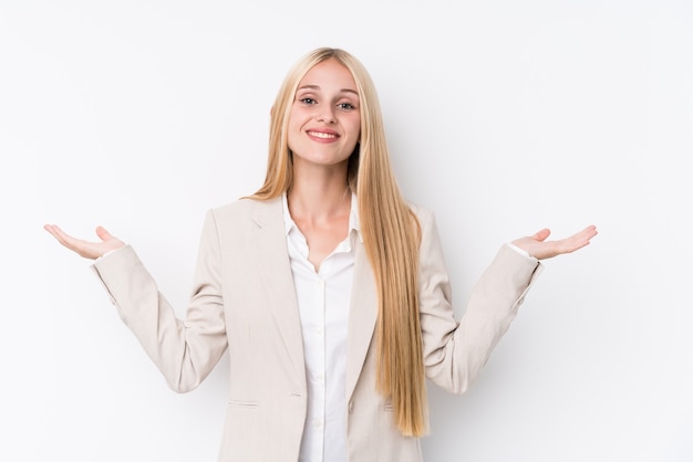 Jonge zakelijke blonde vrouw op wit maakt schaal met armen, voelt zich gelukkig en zelfverzekerd.