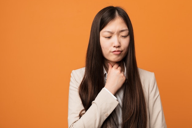 Jonge zakelijke Chinese vrouw lijdt pijn in de keel als gevolg van een virus of infectie.