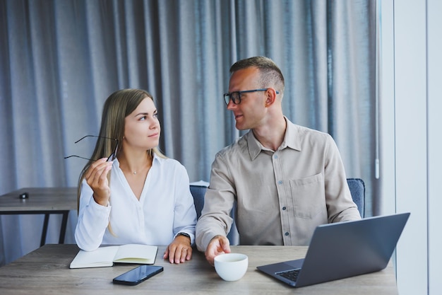 Jonge zakelijke team mannelijke en vrouwelijke collega's die op het werk praten over een nieuw project met een laptop jonge leidinggevenden die een vriendelijk gesprek hebben en samenwerken in teamwerk op kantoor