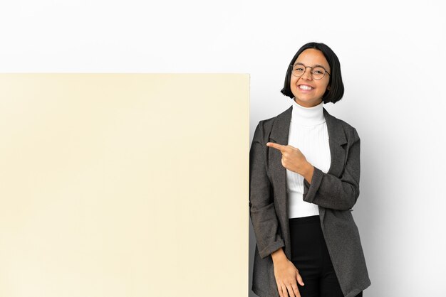 Jonge zaken gemengd ras vrouw met met een grote banner over geïsoleerde achtergrond wijst naar de zijkant om een product te presenteren