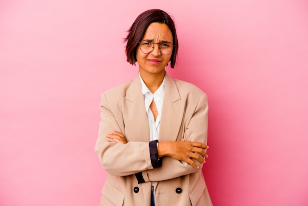 Jonge zaken gemengde rasvrouw die op roze muur verdacht, onzeker wordt geïsoleerd, die u onderzoekt.