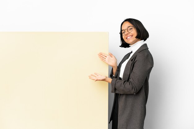 Jonge zaken gemengde rasvrouw met met een grote banner over geïsoleerde achtergrond die handen aan de kant uitbreidt om uit te nodigen om te komen