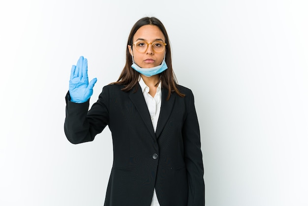 Jonge zaken latin vrouw dragen van een masker om te beschermen tegen covid geïsoleerd op een witte achtergrond staan met uitgestrekte hand tonen stopbord, waardoor u.