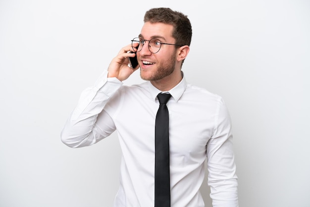 Jonge zakenkaukasische man geïsoleerd op een witte achtergrond die een gesprek voert met de mobiele telefoon