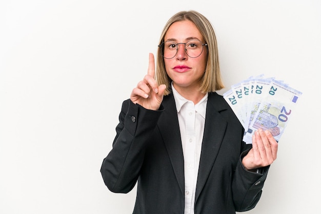 Jonge zakenkaukasische vrouw met bankbiljetten geïsoleerd op een witte achtergrond die nummer één met vinger toont