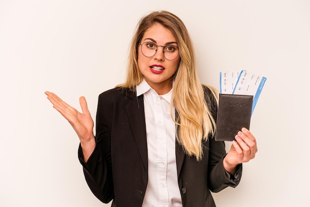 Jonge zakenkaukasische vrouw met een paspoort geïsoleerd op een witte achtergrond verrast en geschokt