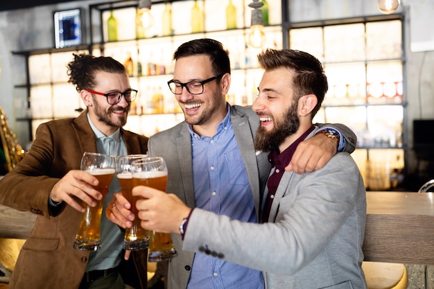 Jonge zakenlieden drinken bier, praten en glimlachen terwijl ze uitrusten in de pub