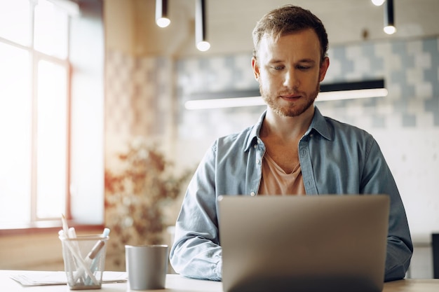 Jonge zakenman die aan computer in het bureau werkt