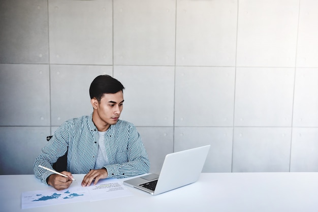 Jonge zakenman die aan computerlaptop werkt in bureau