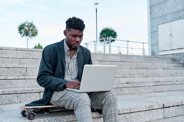 Jonge zakenman die buiten in de stad zit met een laptop