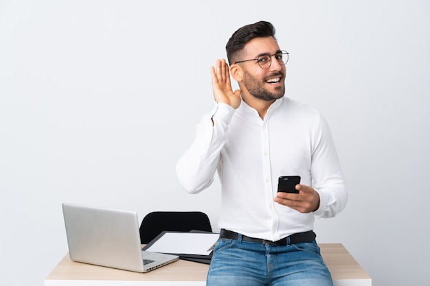 Jonge zakenman die een mobiele telefoon houdt luisterend iets