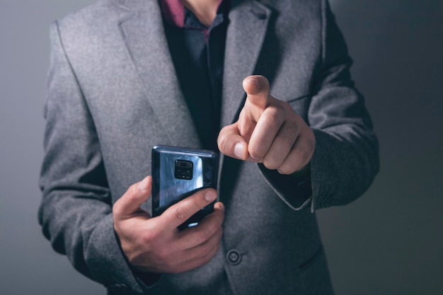 Jonge zakenman die een telefoon vasthoudt en op een virtueel scherm klikt