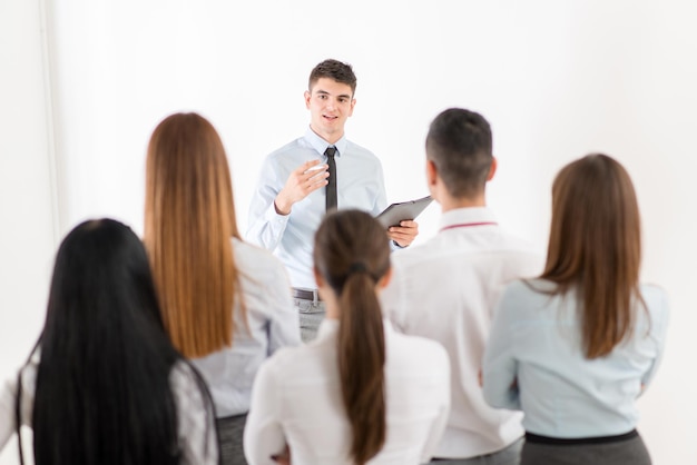 Jonge zakenman die het werkplan van haar collega's uitlegt. Het team luistert.